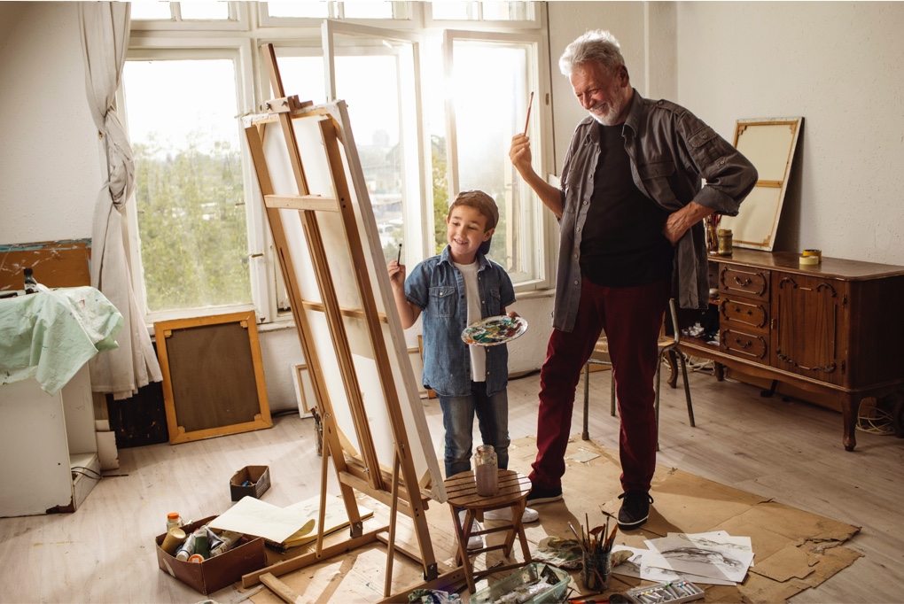 Man and grandson painting on canvas and easel