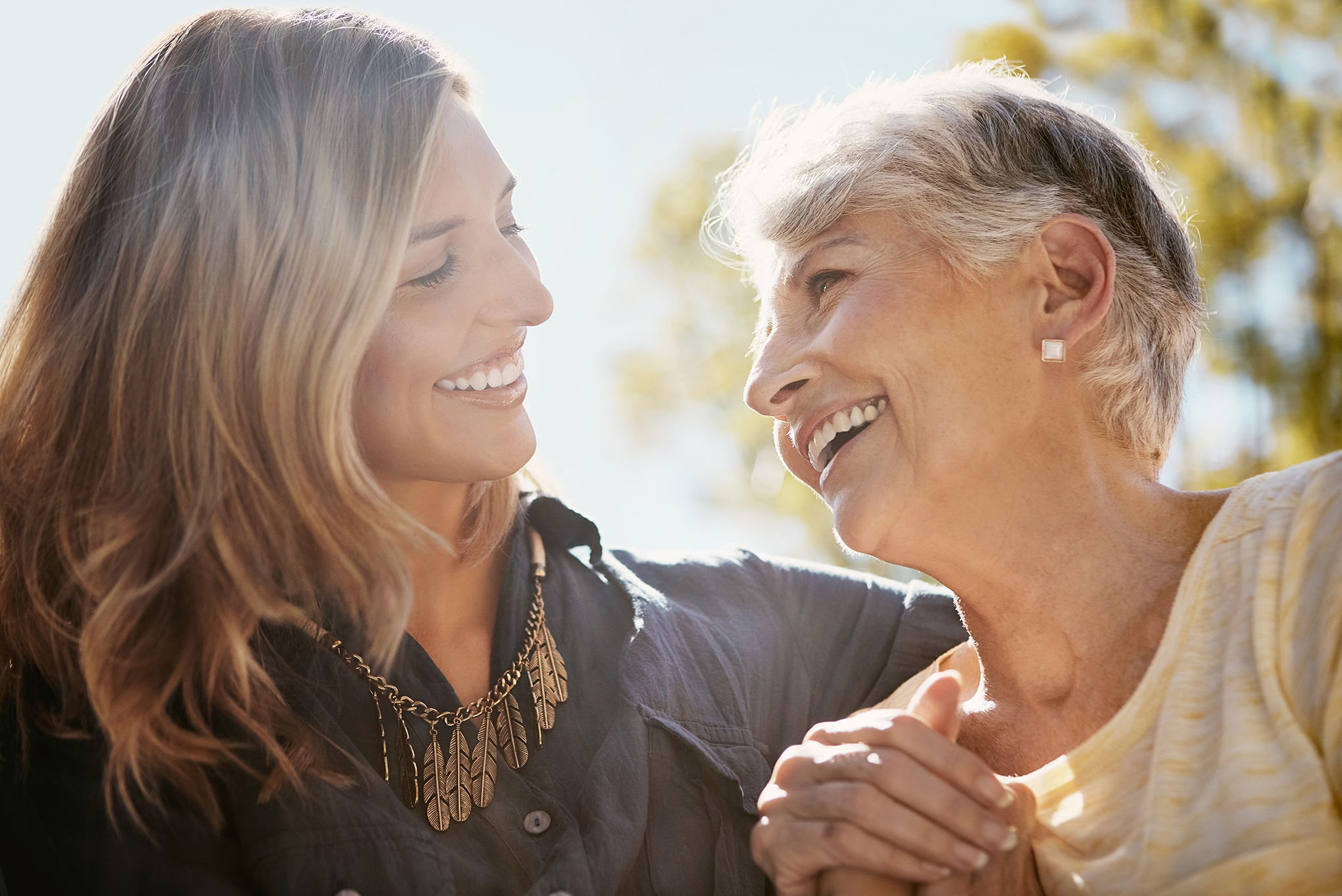 Mature mother and daughter laughing outside