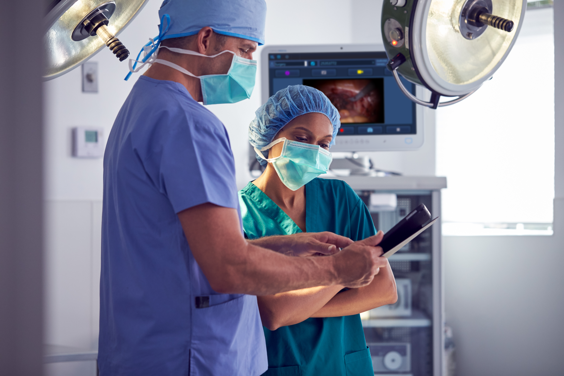 Two surgeons in the OR reviewing a case video on a tablet
