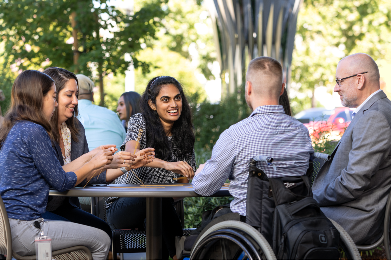 A diverse group of teammates sitting outside at table