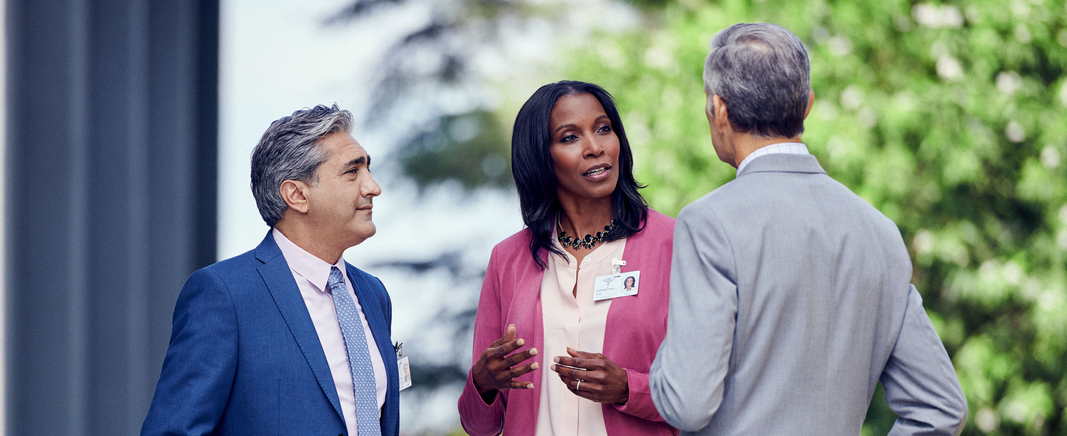 Three hospital executives conversing in a circle.
