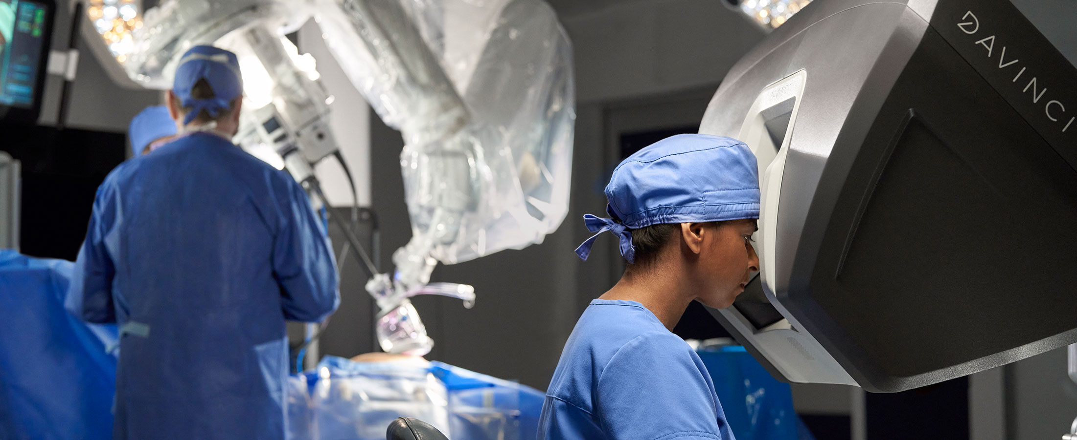 Medical staff shown in operating room with da Vinci SP and the da Vinci surgeon console