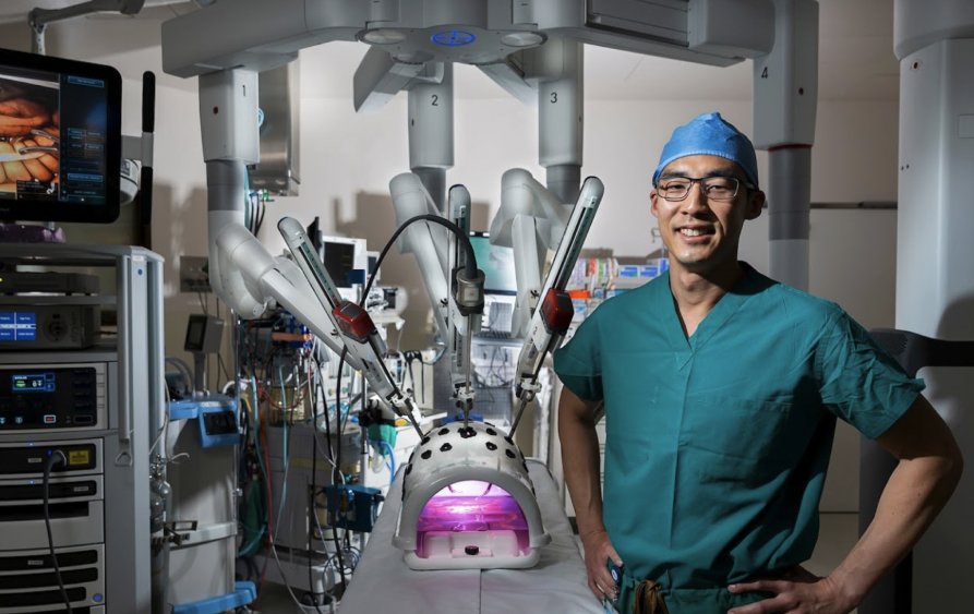 Surgeon Rockson Liu standing in front of a da Vinci Xi surgical system