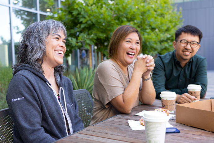 Three employees sitting at a table outside having a coffee break