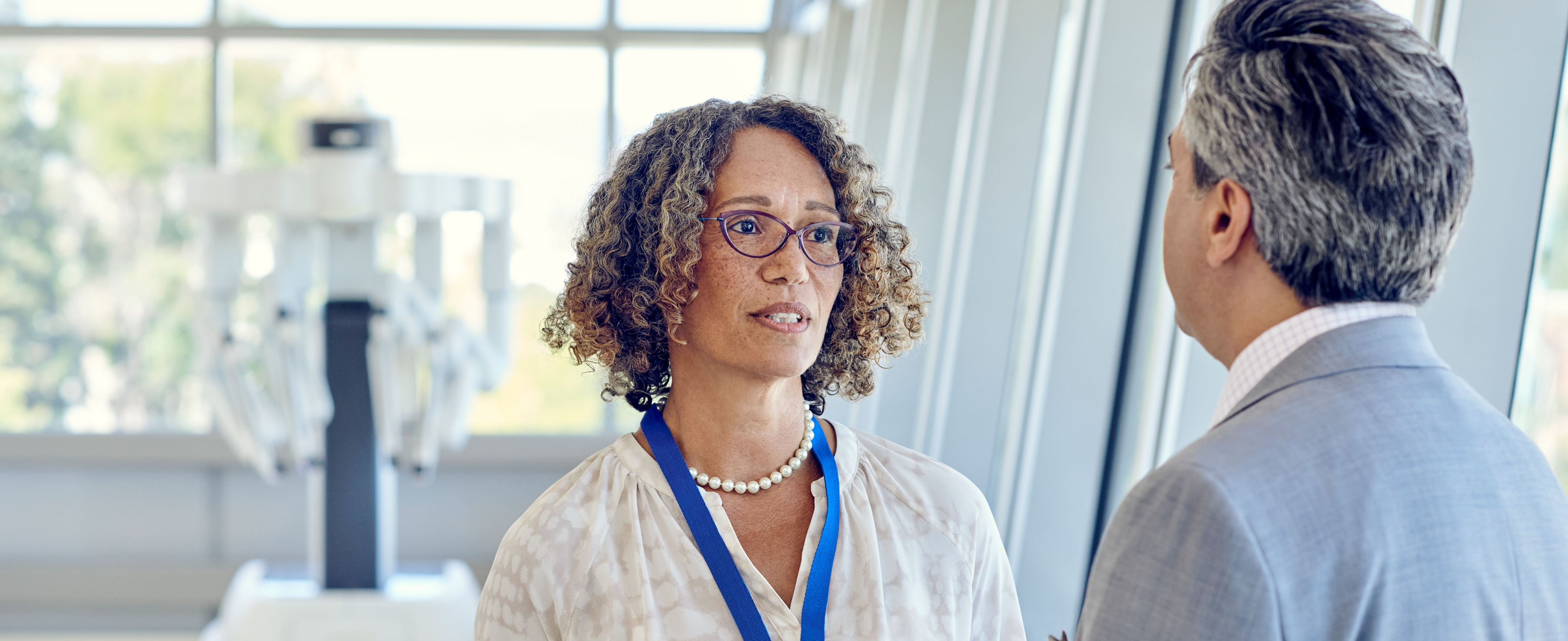A female hospital executive meets with male guest in hallway
