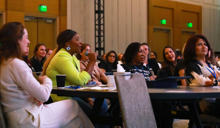 A diverse group of female surgeon audience members engage in live discussion